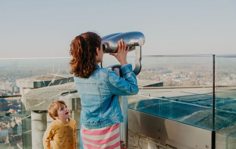Een kind kijkt door de kijker op de Skywalk van de Sint-Romboutstoren
