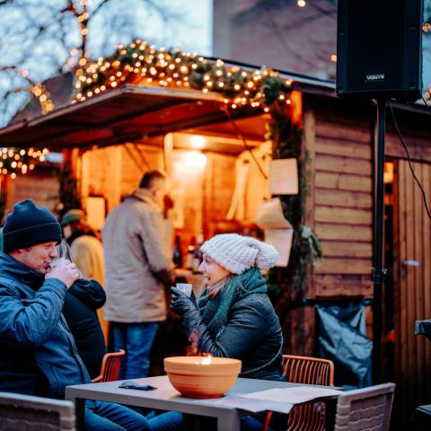 Mensen die iets drinken aan een gezellig standje op de kerstmarkt.